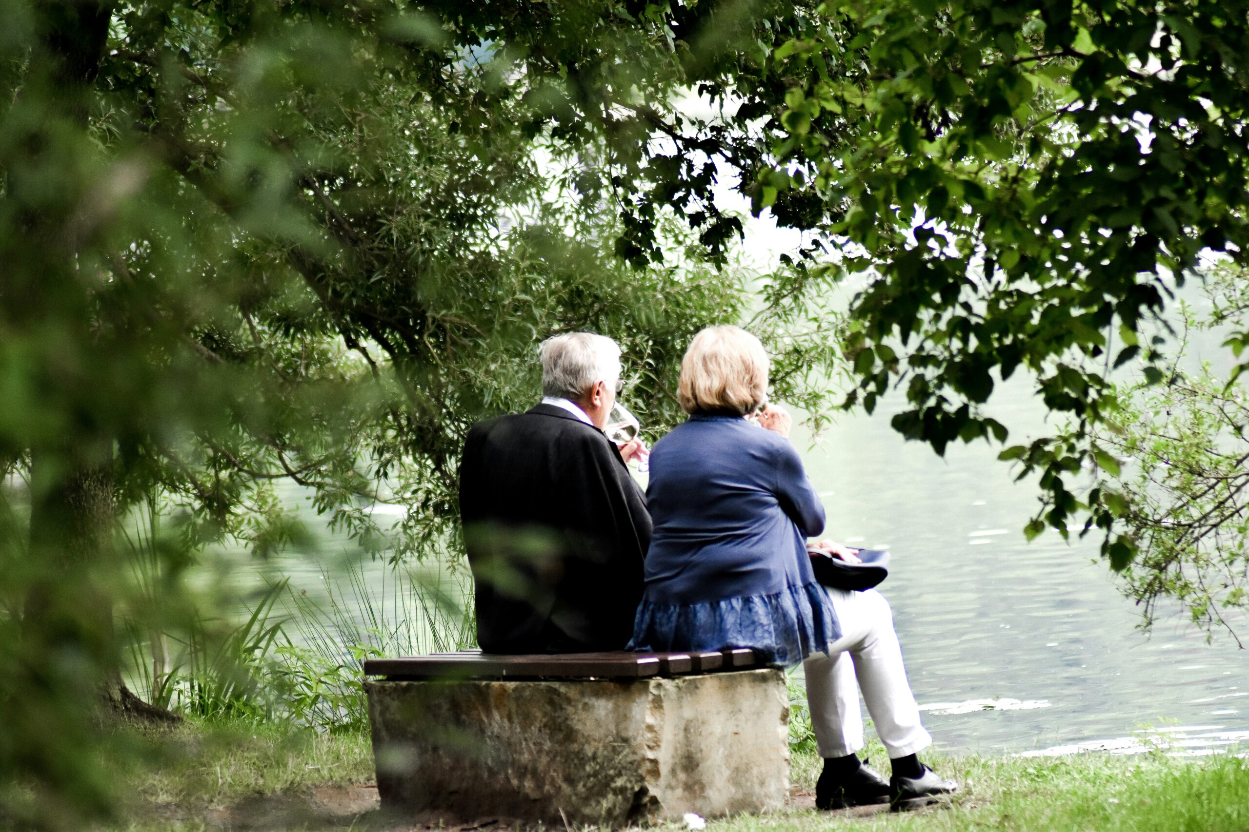 Older couple sitting together on a bench by the water, representing aging in place and maintaining independence.