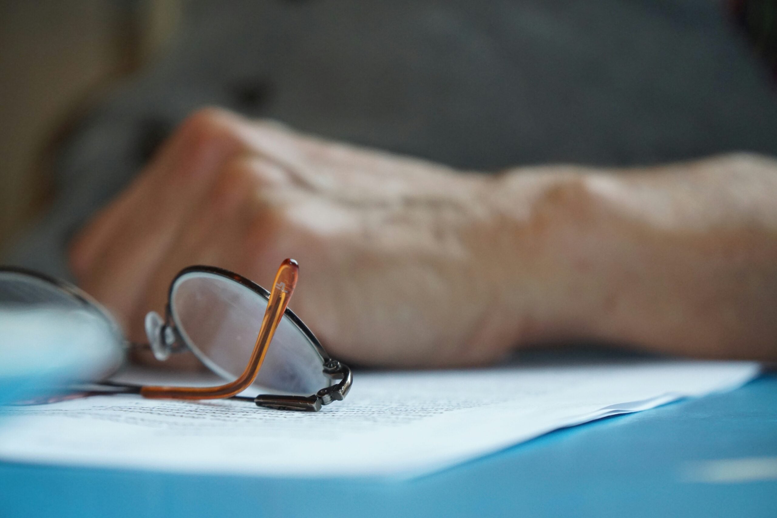 Senior reviewing Medicare paperwork and home care information with reading glasses nearby